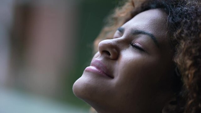 Spiritual black woman closing eyes in contemplation, Brazilian girl opening eye to sky with HOPE