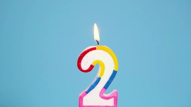 Anniversary video banner with Burning colorful number two candle on Blue Background. 4K resolution anniversary banner.