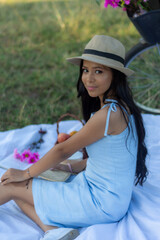 Fototapeta premium portrait of young brunette woman looking at camera sitting on a white blanket on a picnic. 