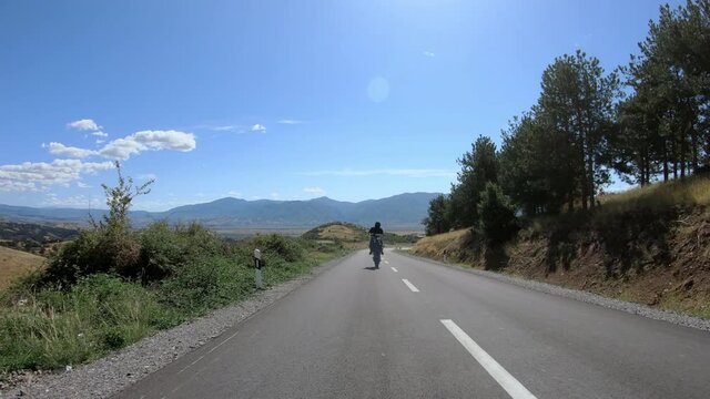 Biker stunt ride biike on mountain rural road and do wheelie on motorcycle