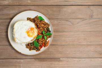 Minced pork with basil rice with fried egg, laying on the wooden floor, top view