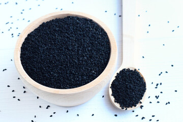 Nasiona czarnuszki w drewnianej misce na białym tle