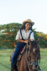 young brunette girl long black hair smiling riding a horse in the field on a sunny day
