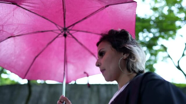 Woman opening umbrella parasol outside to protect from rain walking