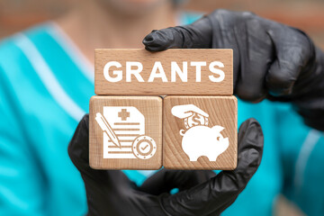 Concept of grant. Grants for medical innovation, research, education. Doctor holding wooden blocks with grants concept.