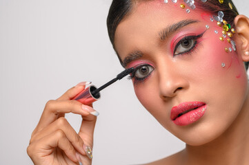 Woman wearing pink makeup and brushing eyebrows