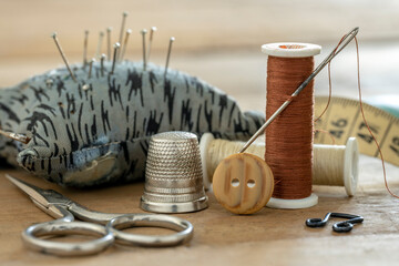 Close up of sewing kit consisting of thimble, needle, button, spools of thread, clasp, scissors,...
