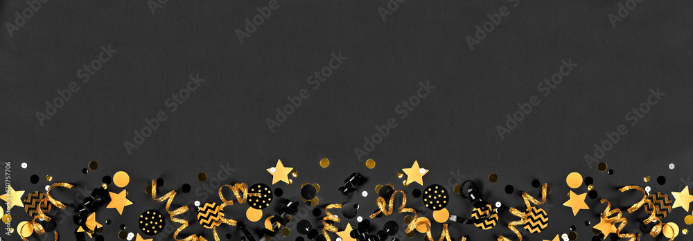 Poster new years party bottom border with glittery black and gold streamers and confetti. top down view on 