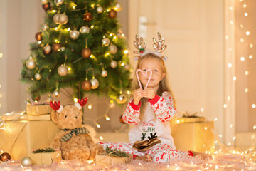 Beautiful caucasian little girl five years old wearing Christmas pajamas when having fun at home during winter holidays. Merry xmas and happy new year 2022