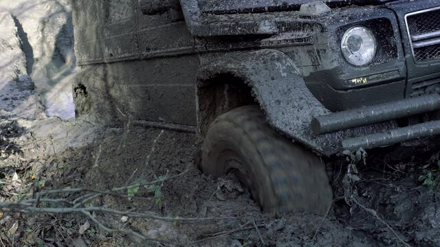 Dirty car tire close up, mud tires. Off-road, dirty car wheel among brown dust. Slow motion. Car wheels on steppe terrain splashing with dirt. SUV or offroader on mud road. Offroad car in action.