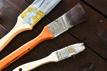 A close up image of several old used paint brushes with dried paint. 