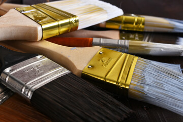 A close up image of several old used paint brushes with dried paint. 