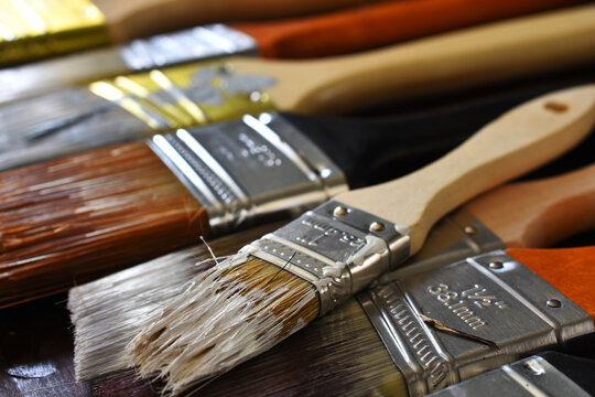 A close up image of several old used paint brushes with dried paint. 