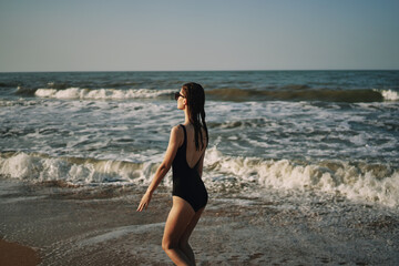 Fototapeta na wymiar woman in black swimsuit walking on the beach ocean summer