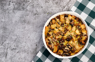 Oven Roasted Potatoes with mushrooms in a white baking dish on a dark grey background. Top view, flat lay