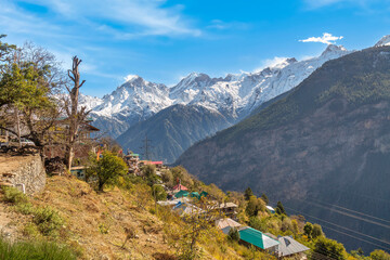 Fototapeta na wymiar Aerial view of scenic mountain village with residential houses with majestic Kinnaur Kailash Himalaya range on way to Chitkul, Himachal Pradesh, India