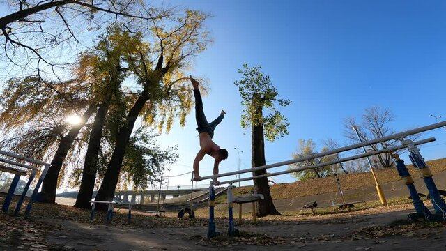 Gymnast does tricks on parallel bars outdoor. Concept of willpower, motivation and healthy lifestyle