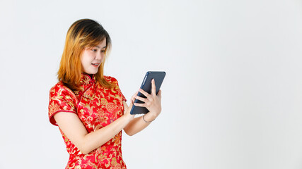 Studio shot of teen Asian young teen female model in beautiful red gold Chinese traditional cheongsam qipao shirt stand holding touchscreen tablet with mile face on white background