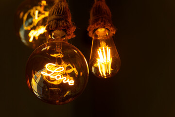 An electric light bulb with a glowing filament inside in the form of the word LOVE