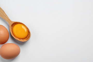Raw chicken eggs and spoon with yolk on white background, flat lay. Space for text - obrazy, fototapety, plakaty
