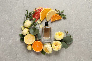 Flat lay composition with bottle of perfume and fresh citrus fruits on light grey table