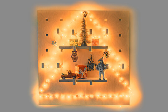 Christmas tree wall decor of lighted wood pegboard xmas ornaments decorations. Shaped string light, miniature gifts, stockings, table top trees. Home shelves.