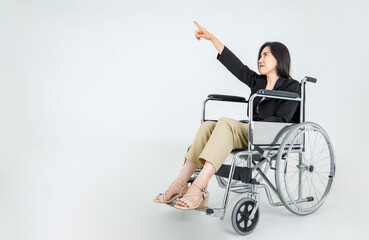 Strong Asian paralysis woman on rehabilitation wheelchair intentionaly pointing finger to higher...
