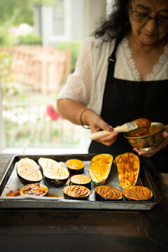 Woman brushing spicy pesto on eggplant 