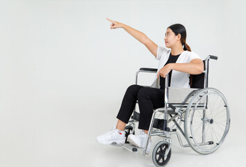 Beautiful Asian disabled girl cheerfully sit on medical wheelchair in hospital optimistically laugh and happy with hands raising up as physical injury recovery by strong rehab