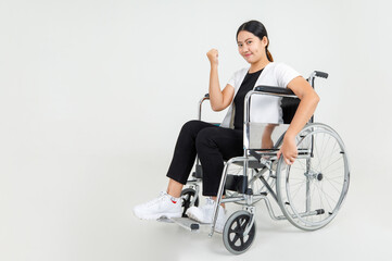 Fototapeta na wymiar Beautiful woman patient show clenched fist and sit on wheelchair to express strong health during rehabilitation in hospital