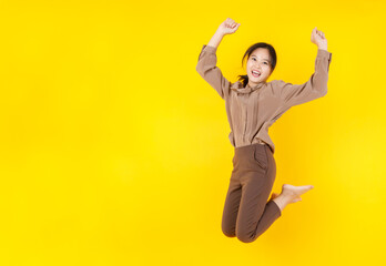 Obraz premium Lovely Asian girl lively jumping up high and clench fits with laugh and cheerful as exciting, satisfy and happy on deal success as expected