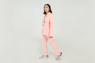 Lovely Asian woman enjoy walking style with sneaker and clothing of pink business suit