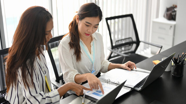 Two of business employees analysing and checking business data report