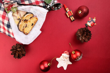 Christmas xmas decoration ornament bell gift checked fabric cloth wrap sliced stollen fruit cake food pine fruit on red background