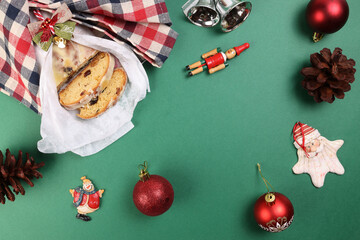 Christmas xmas decoration ornament bell gift wrap sliced stollen fruit cake food pine fruit on green background