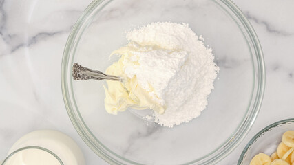 Cream cheese and powdered sugar close up in a glass bowl, flat lay, copy space. Whipped cream cheese desert recipe