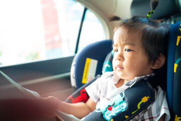 Baby boy sitting on carseat safty in cay read book