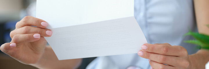Woman reading letter while sitting at table with open envelope