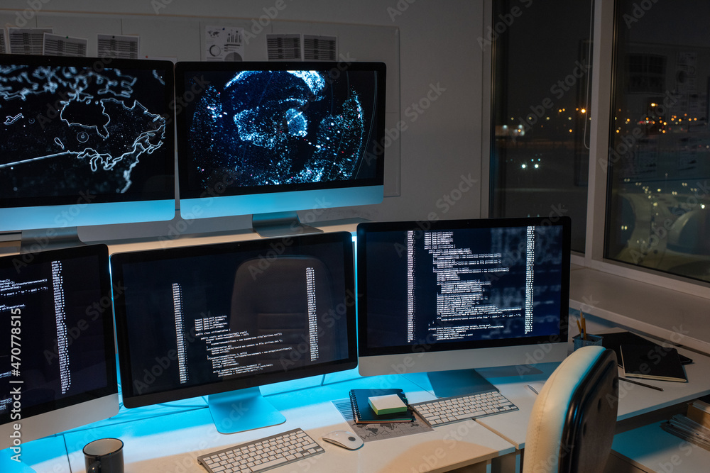 Fototapete Part of large openspace office of programming company with long desk and several computer monitors with coded data