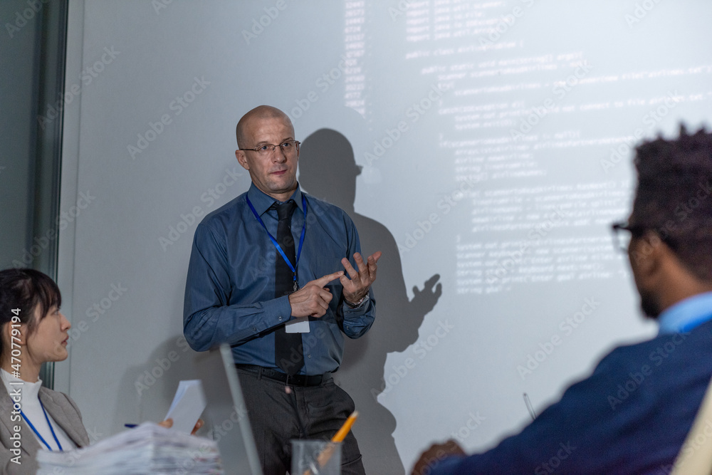 Poster Experienced it-developer in formalwear explaining new way of decoding data to audience during presentation