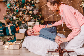 young woman tickles the bare feet of a sleeping child. Christmas and gifts