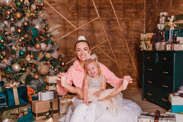 smiling mother tickles her two-year-old daughter's bare feet for Christmas. laugh with happiness