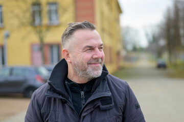 Bearded man looking aside with a quiet smile of satisfaction