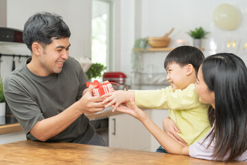 Anniversary, Happy birthday party in family, asian young parent father or dad, mother or mom and little cute boy or child celebrating give gift,  present, surprise celebration at home. Lovely moment.