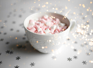 Fototapeta na wymiar cup with marshmallows on a white background with silver snowflakes