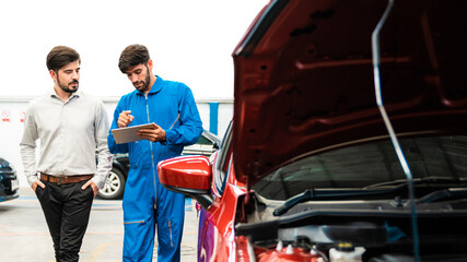 Mechanic man shows report on a digital tablet to the Middle East client at garage, A man mechanic...