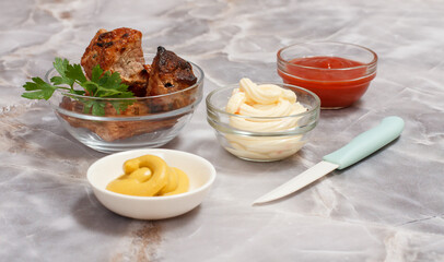 Grilled pork in a bowl with sauces and greens.