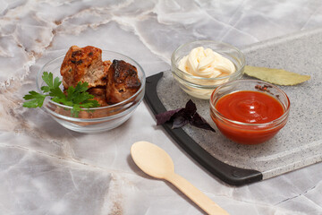 Grilled pork in a bowl with sauces and greens.