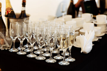 A row of glasses partially filled with champagne are lined up prepearing to be served