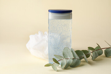 Bottle of shower gel, sponge and eucalyptus branch on color background